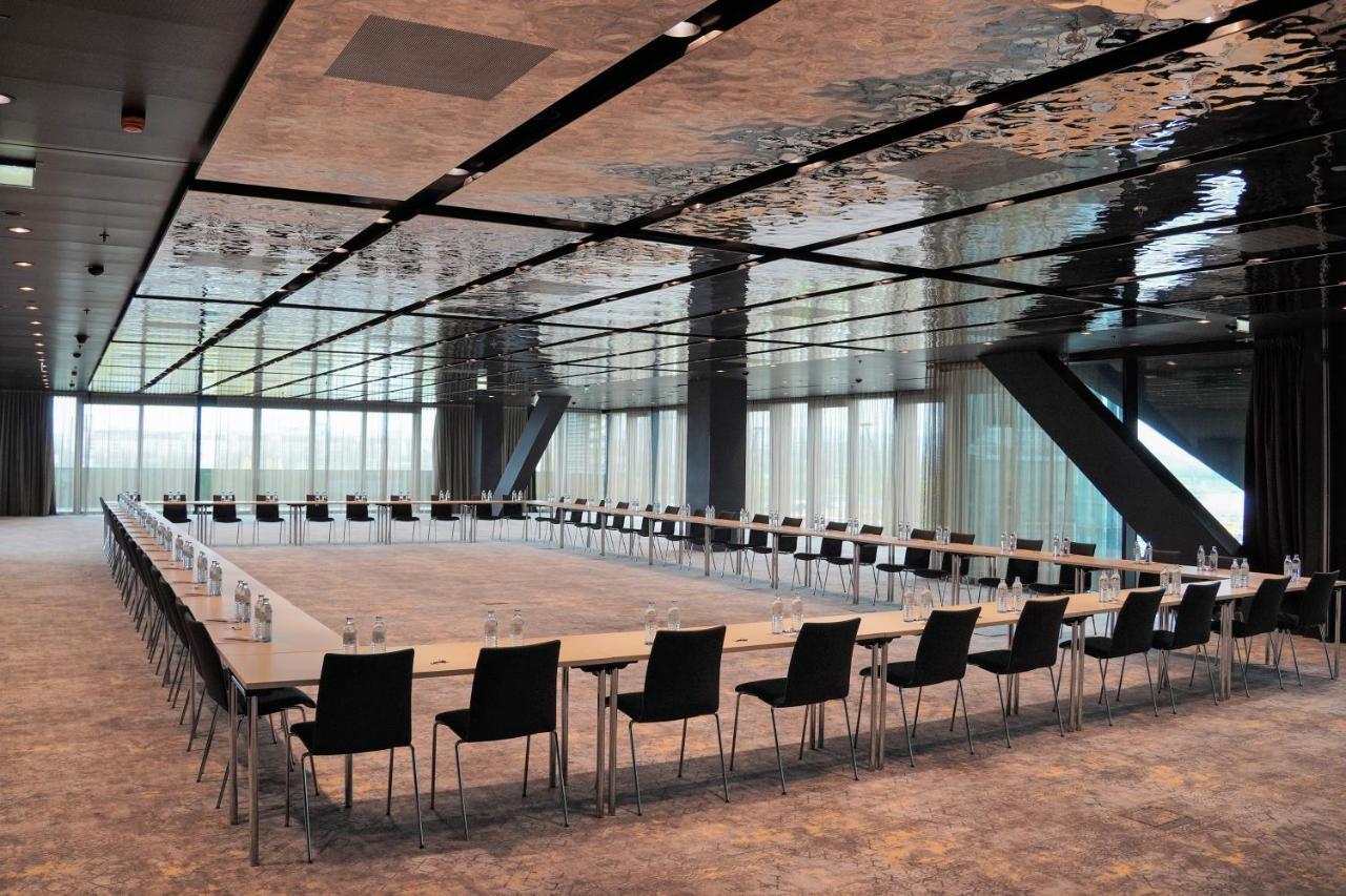 เมเลีย เวียนนา Hotel ภายนอก รูปภาพ The photo shows a modern conference room with a long rectangular table arranged in a U-shape. The table is flanked by multiple black chairs. The room features a sleek, reflective ceiling that gives a contemporary feel, and large windows allow natural