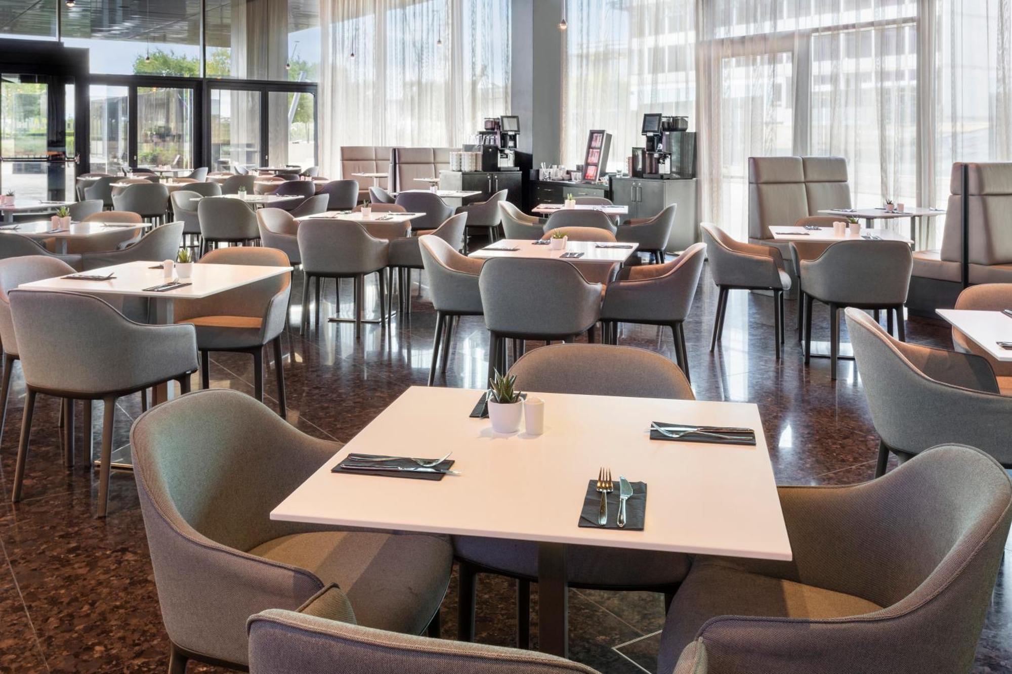 เมเลีย เวียนนา Hotel ภายนอก รูปภาพ The photo shows a spacious dining area in a restaurant or café. There are several tables arranged throughout the space, each with light-colored tabletops and comfortable chairs. The decor appears modern and minimalistic, with large windows allowing n